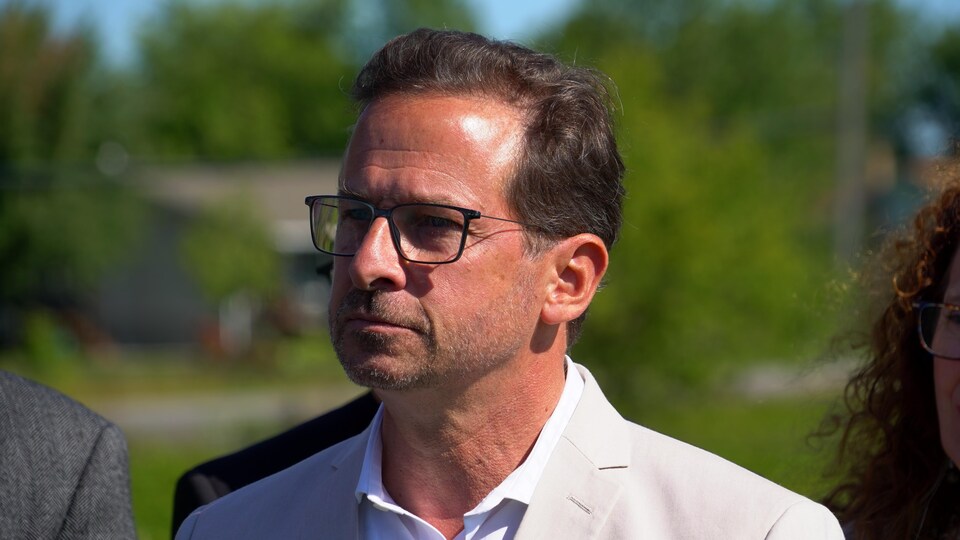 Yves François-Blanchet tient un point de presse au soleil, près d'un champ de soya.