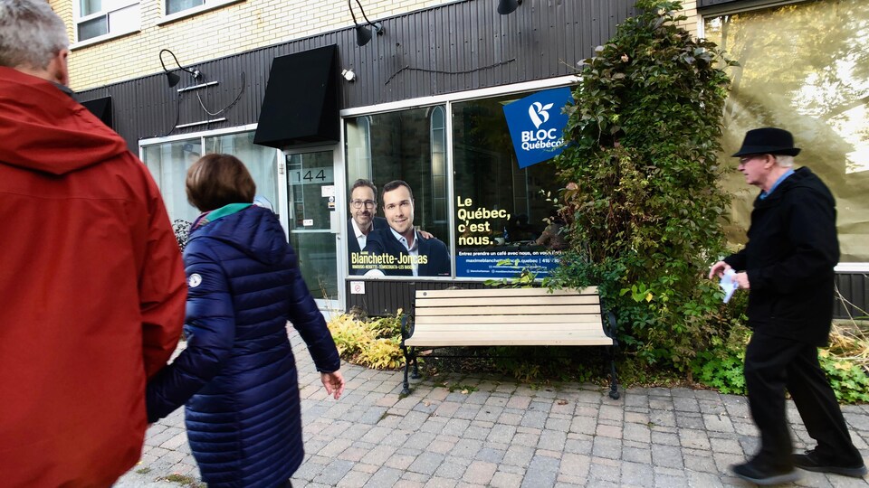 Trois personnes passent devant le bureau de campagne.<br>