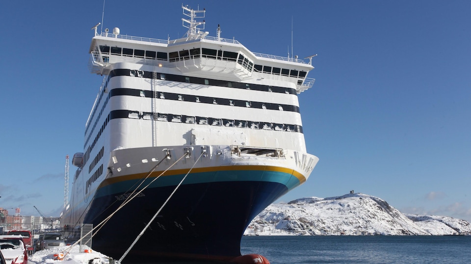 Le navire au port en hiver près d'une côte enneigée.