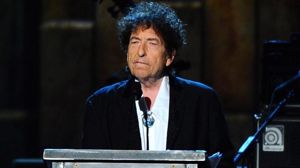 Bob Dylan parle dans un micro, derrière un podium.