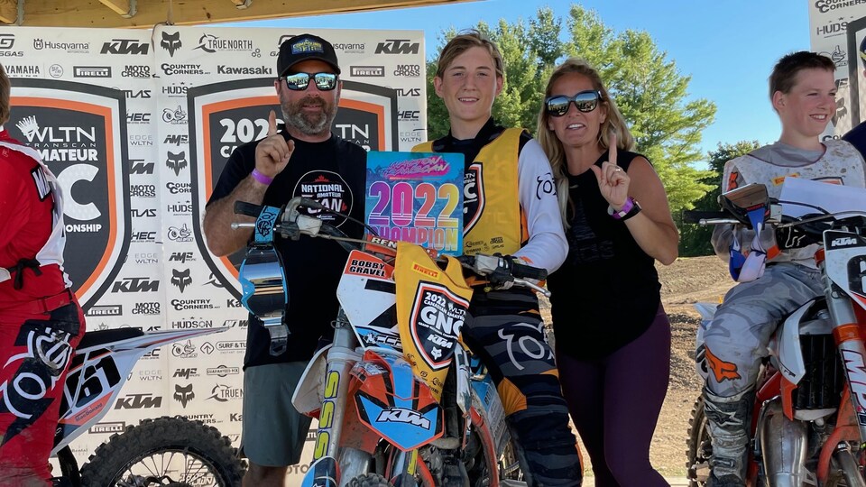 Un jeune homme célèbre son championnat entouré de ses parents.