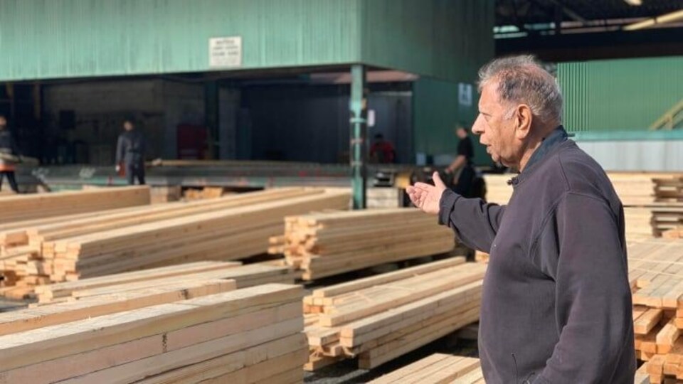Un homme avec des planches de bois en arrière-plan.