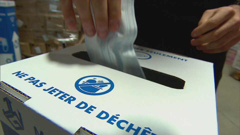 Un homme met un masque dans une boîte de recyclage