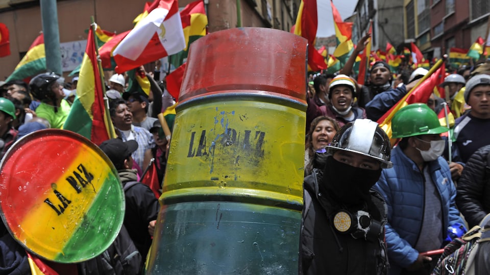 Des manifestants se cachent derrière des boucliers de fortune aux couleurs de la Bolivie et portant l'inscription La Paz. 