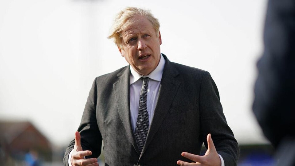 Boris Johnson répond aux questions des médias sur un terrain de soccer.