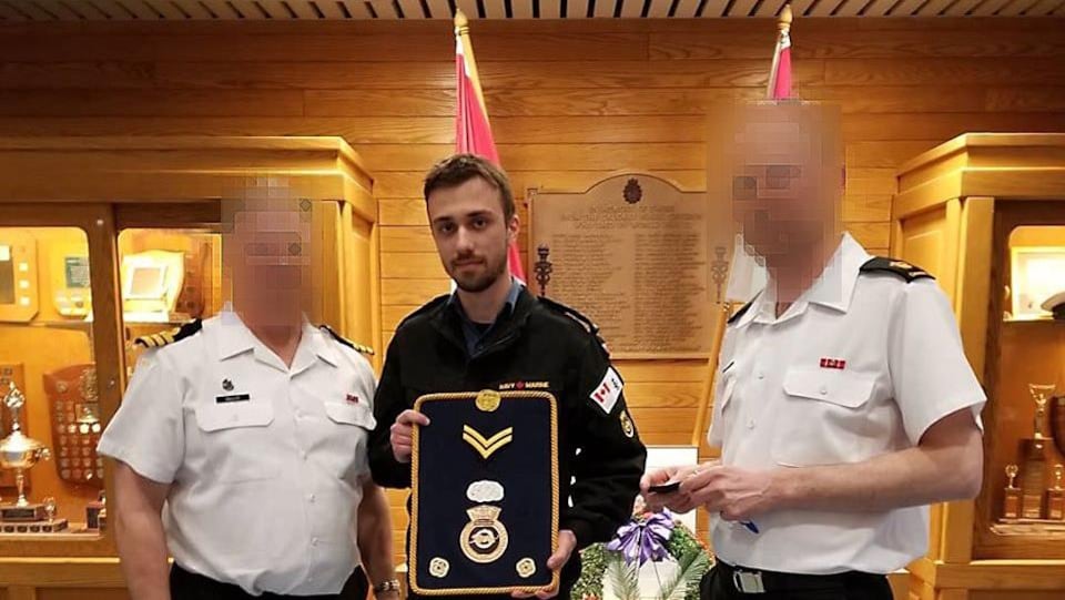 Un jeune homme en uniforme, accompagné de deux officiers, tient une enseigne militaire.