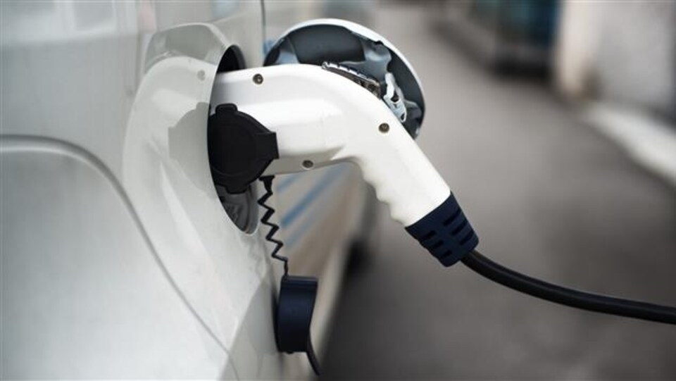 Plan serré d'une voiture électrique branché à une borne de recharge.