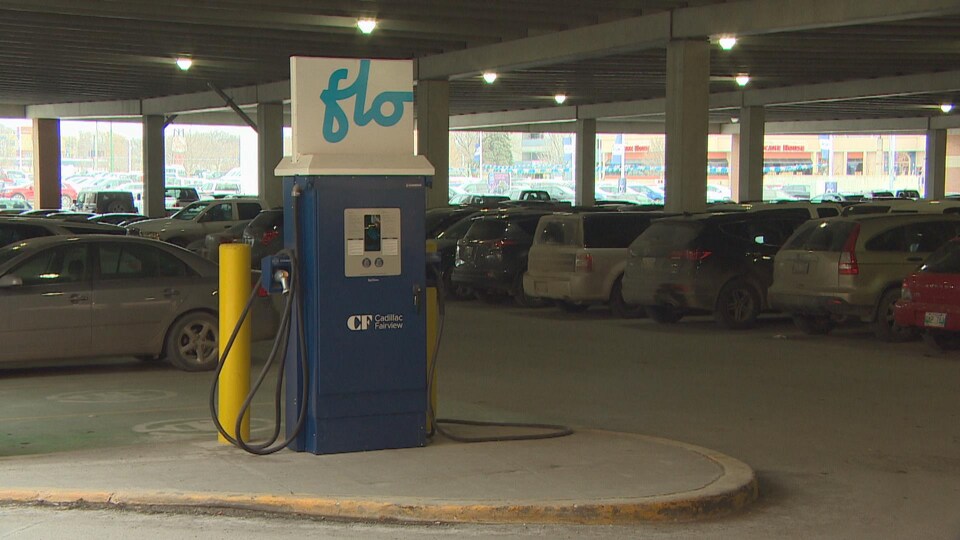 Une borne de recharge bleue et blanche portant les lettres flo se trouve au rez-de-chaussée d'un stationnement à étage.
