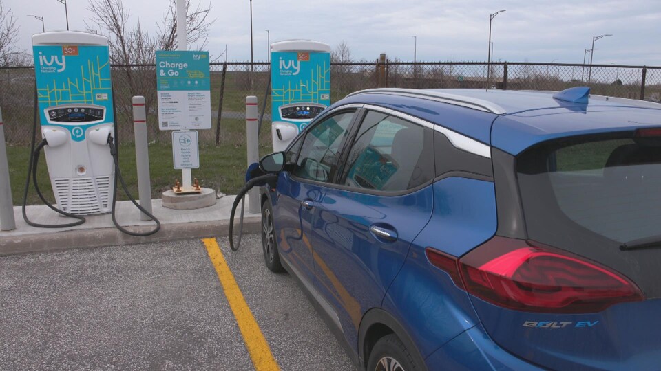 An electric vehicle in a parking lot with a charging station in Windsor. 