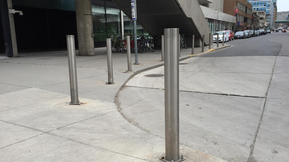 Des bornes de métal installées sur le trottoir le long de la rue pour empêcher les véhicules de happer les piétons.