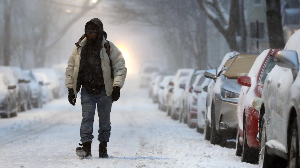 Un homme marche dans une rue couverte de neige.