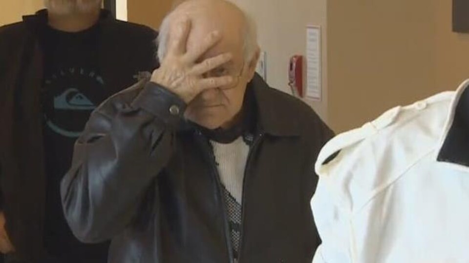 Delmore Boudreau se masque le visage d'une main en marchant dans le palais de justice