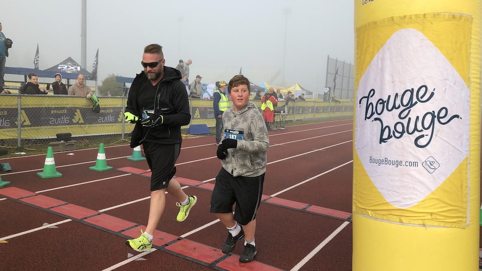 Un homme et un garçon courent sur une piste d'athlétisme.