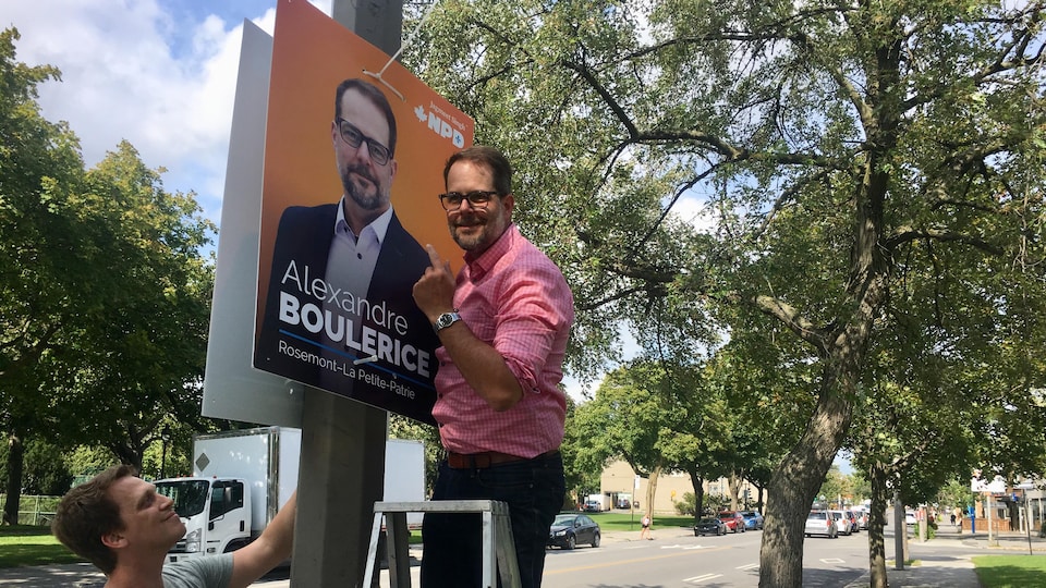 Alexandre Boulerice dans un escabeau en train d'installer une des ses pancartes électorales.