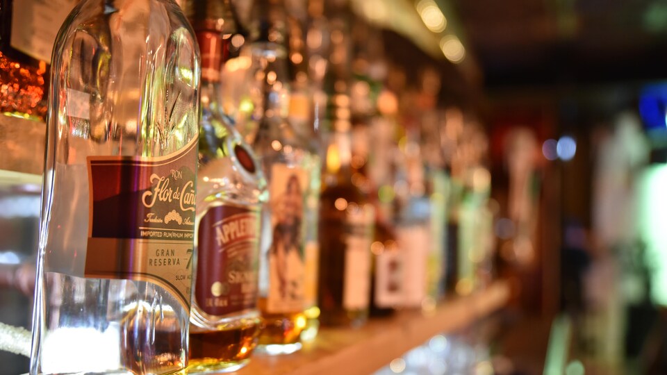 Des bouteilles d'alcools sur une tablette dans un bar. 