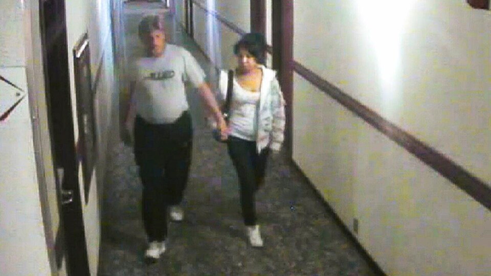 Un homme et une femme marchent main dans la main dans un corridor.