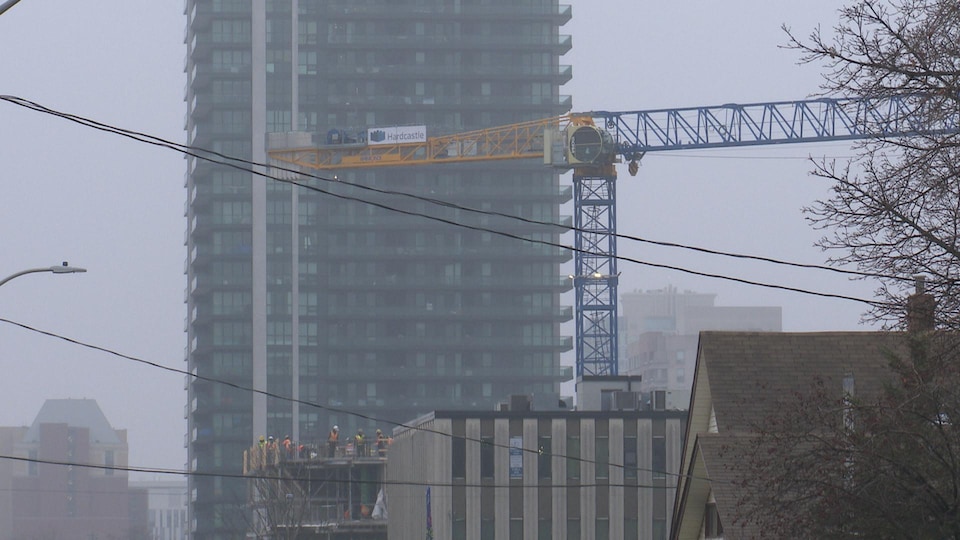 We see a crane in front of a building with workers busy on a construction site. 