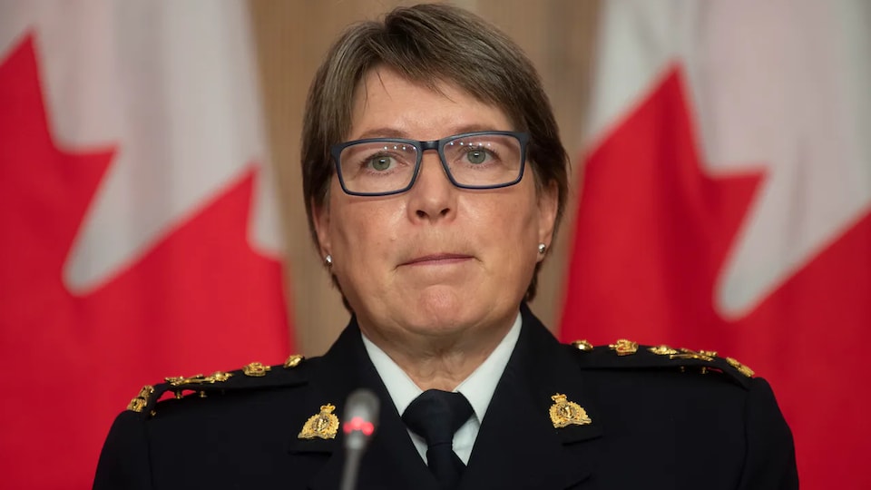 Brenda Lucki, in uniform, in front of a Canadian flag.