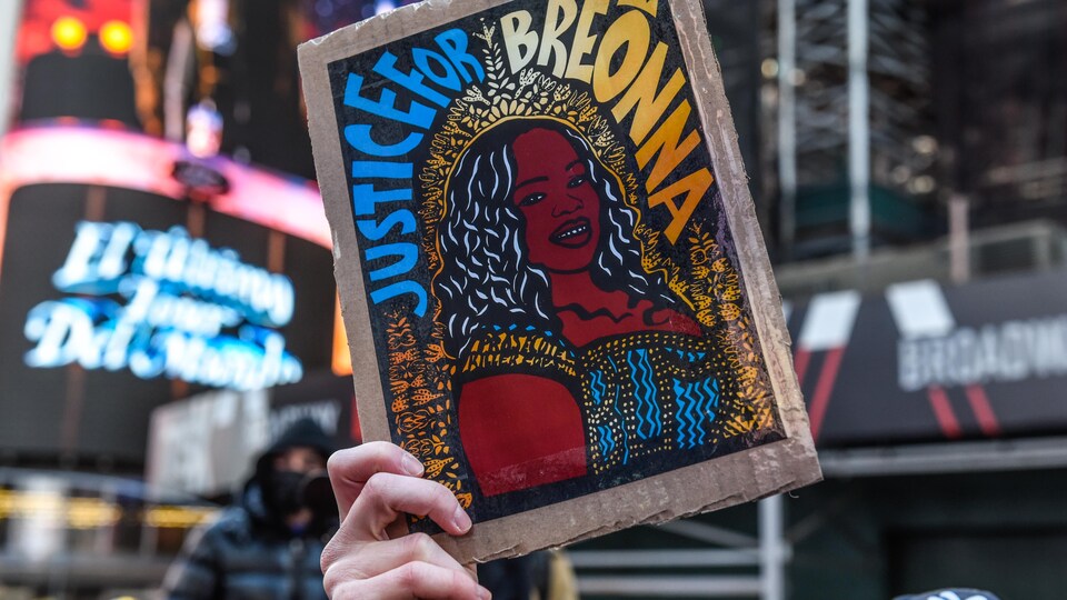 Une main brandit une illustration de Breonna Taylor.