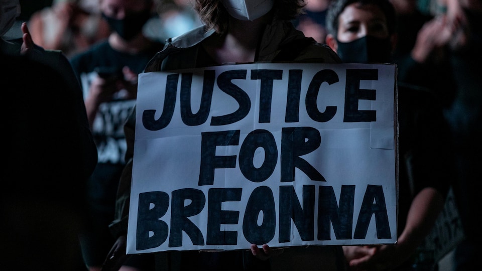 Une femme dans une foule tient une affiche sur laquelle on lit : « Justice for Breonna Taylor ».