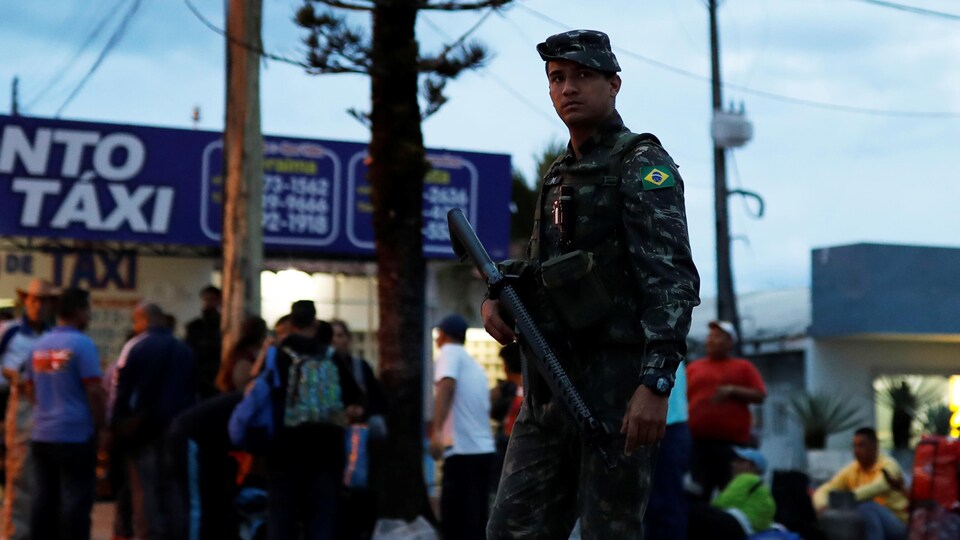 Des soldats de l'armée patrouillent dans une rue à côté des Vénézuéliens après avoir vérifié leur passeport ou leur carte d'identité à la frontière de Pacaraima.