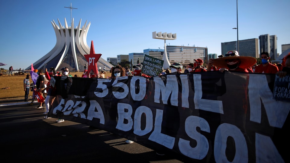 Une large bannière dénonçant le président Bolsonaro dans le décor de Brasilia.