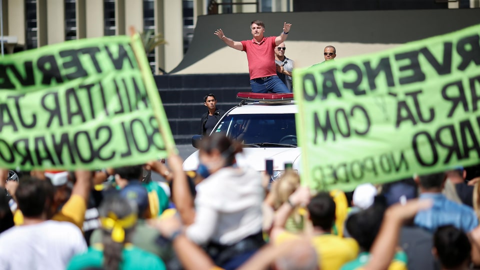 Jair Bolsonaro est debout dans une camionnette et s'adresse à la foule.