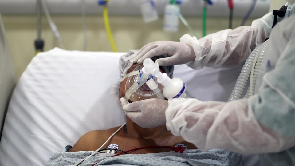 Un médecin ajuste un masque d'oxygène à un patient dans un hôpital.