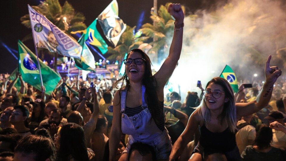 Two girls, sitting on the shoulders of the two men, raised their arms in the air.