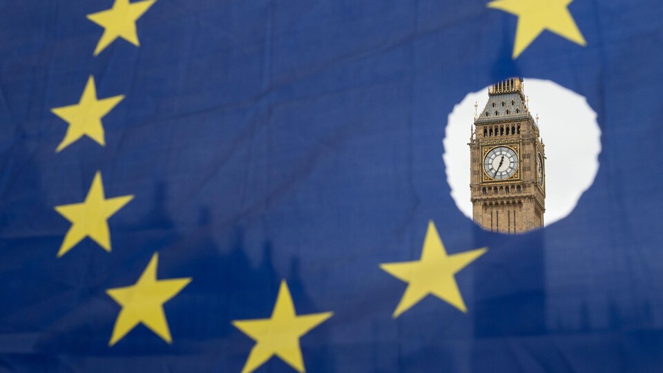 Un drapeau de l'Union européenne avec l'une des étoiles symboliquement découpées devant les chambres du Parlement.
