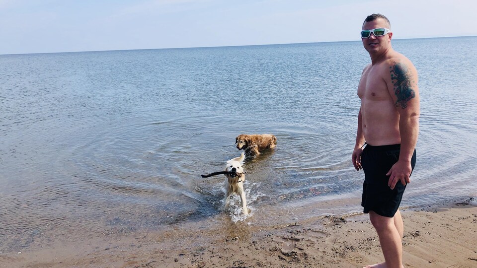 Brian Boudreau marche sur la plage avec ses deux chiens. 