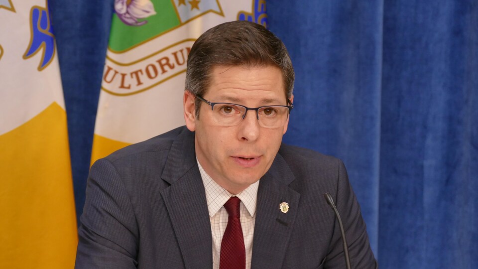 Le maire Brian Bowman est photographié en gros plan; on voit derrière lui une partie des drapeaux de la ville.