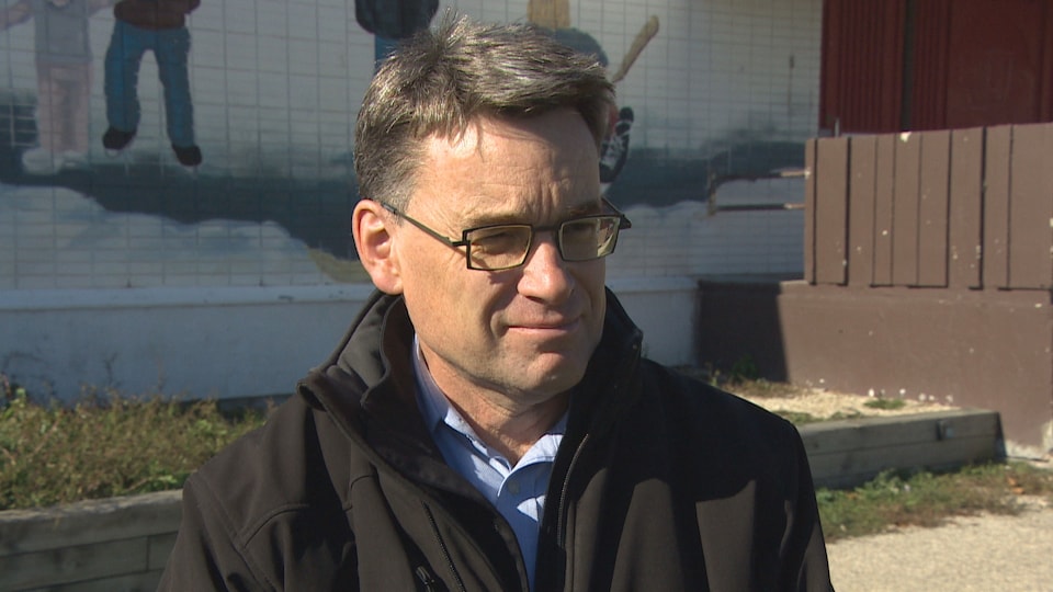 Un homme à lunettes, devant l'aréna de Saint-Vital, en entrevue avec Radio-Canada.