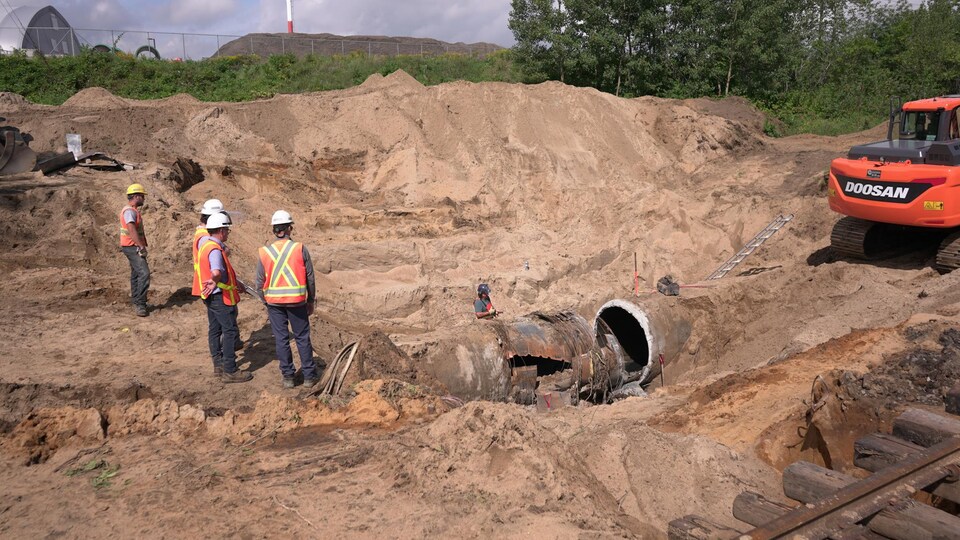 Des travailleurs inspectent une canalisation brisée.