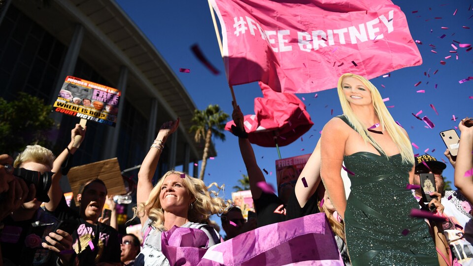 Des admirateurs de Britney Spears fous de joie près d'un palais de justice, qui lancent des confettis et qui tiennent des affiches de la chanteuse.