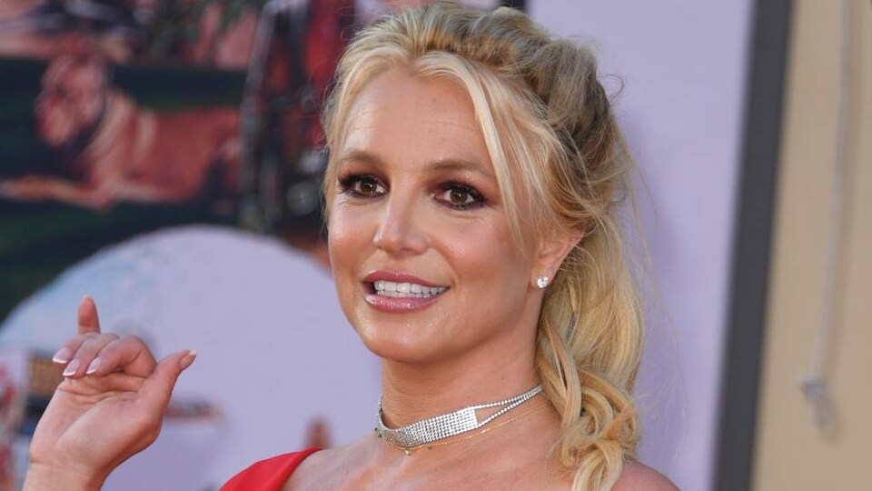 Britney Spears porte une robe rouge et un collier. 