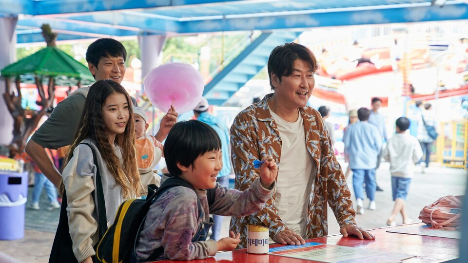 Un adulte et trois enfants coréens sourient au comptoir d'un parc d'amusement.