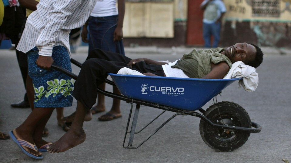  Un Haïtien présentant les symptômes du choléra est transporté dans une brouette dans le bidonville de Cité-Soleil à Port-au-Prince.