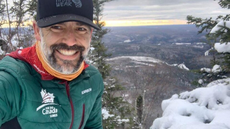 Bruce Guitard souriant entouré de neige.