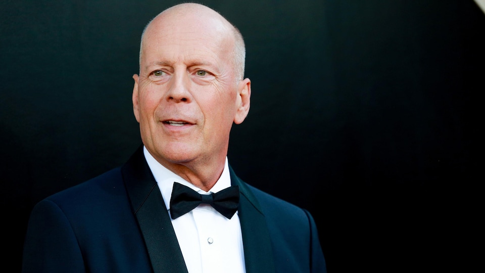 L'acteur Bruce Willis en tuxedo sur un tapis rouge.