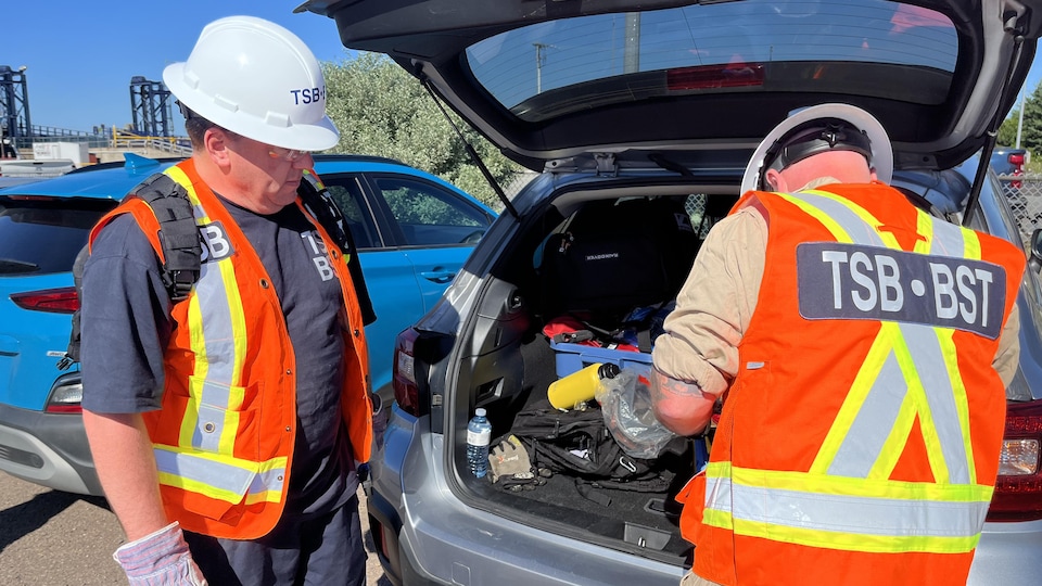 Deux employés du Bureau de la sécurité des transports vérifient leur équipement dans leur voiture.