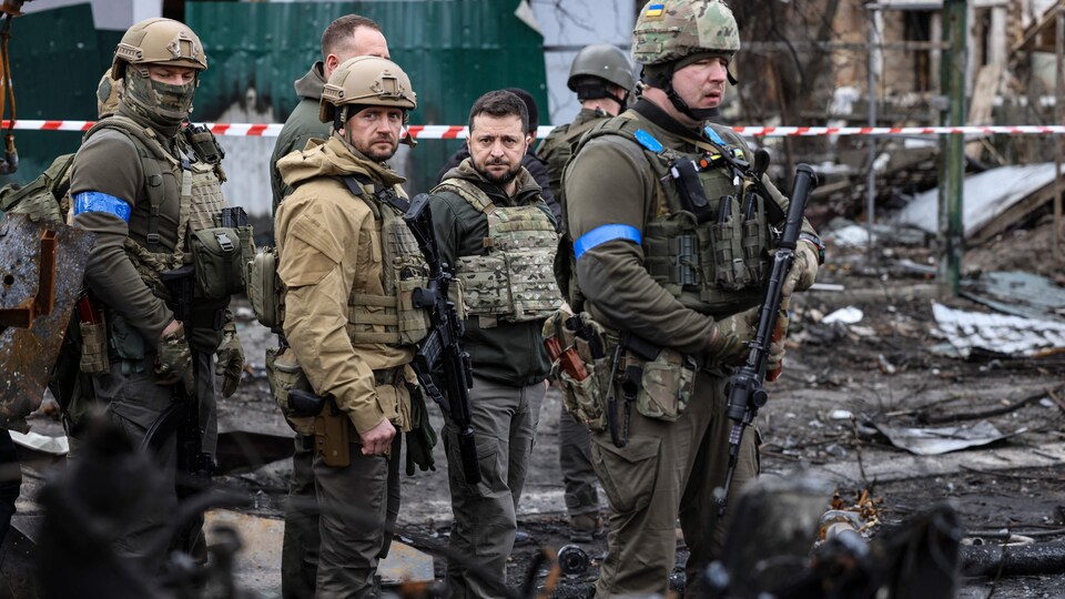 Le président ukrainien se tient au milieu de soldats, dans des ruines.