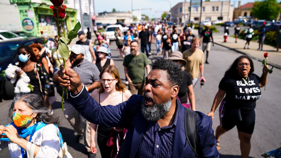 Une foule de personnes manifestent devant un supermarché.