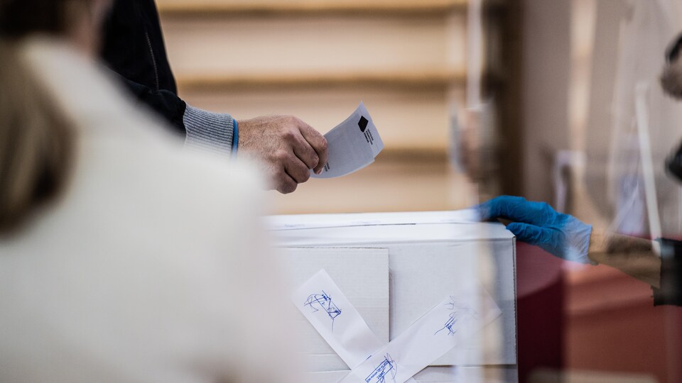 Un homme s'apprête à mettre son bulletin de vote dans l'urne.