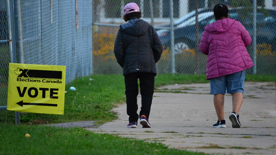 Deux femmes marchent devant un bureau de vote.