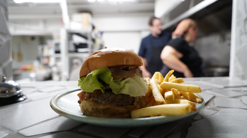 Un burger dans une assiette avec des frites.