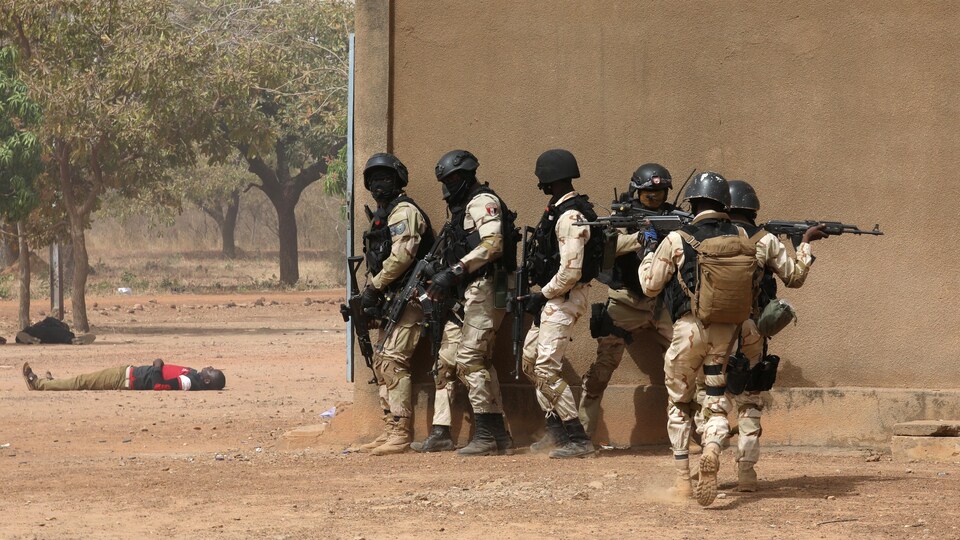 Des soldats armés et un homme gisant au sol