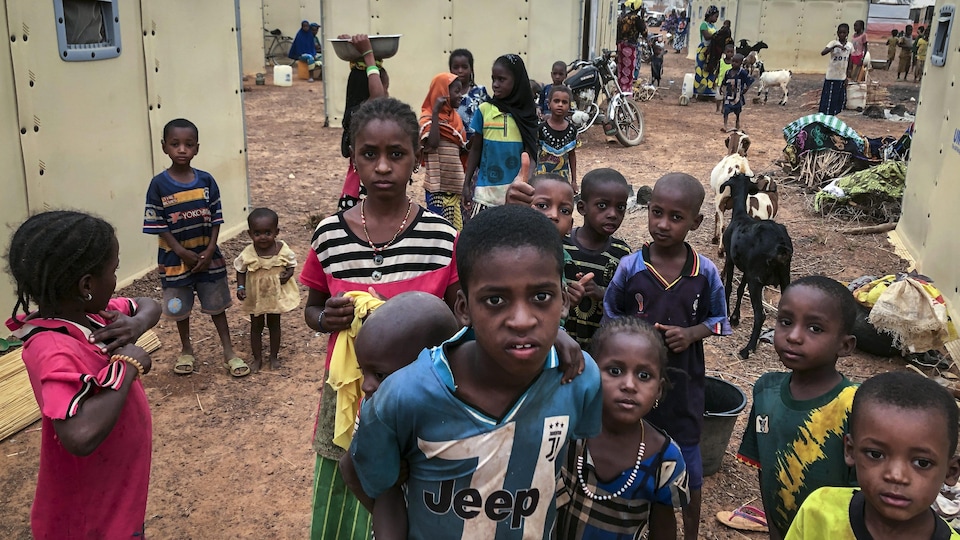 Des enfants rassemblés devant l'objectif de la caméra dans un camp de réfugiés.