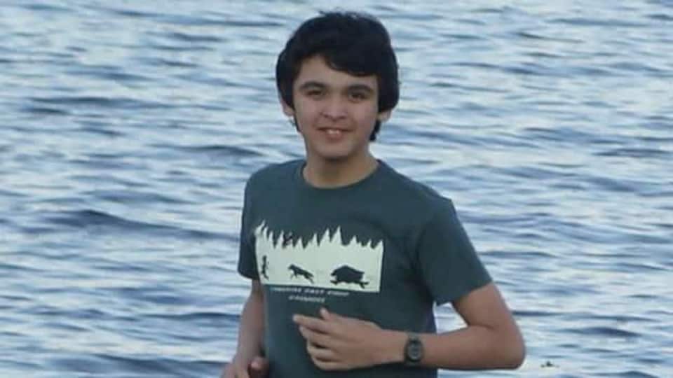 Un adolescent en t-shirt sur le bord de l'eau en été.