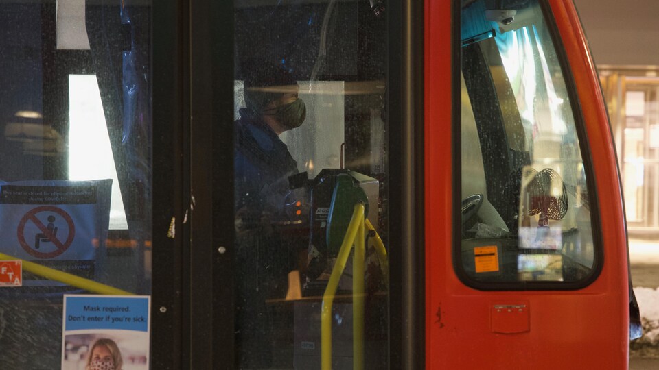 Le chauffeur masqué derrière les portes de son autobus.